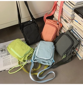 Detailed view of lightweight nylon crossbody bags in various colors on a textured floor