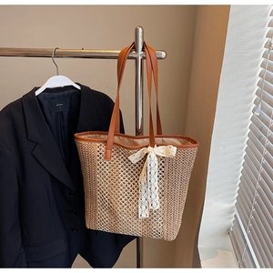 Détail du sac cabas en paille tissée avec anses en cuir marron et nœud en dentelle
