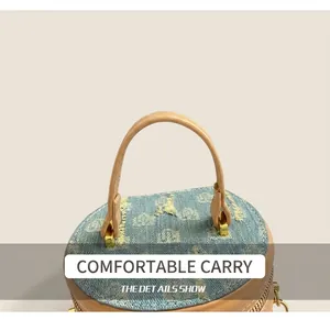 Close-up of denim bucket bag top with frayed edges, khaki leather handles and gold clasp