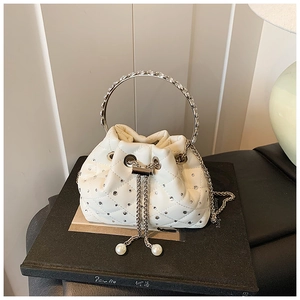 Close-up of white quilted bucket bag with rhinestone round handle and pearl drawstring