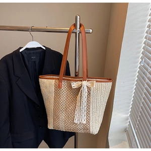 Détail du sac cabas tissé avec poignées en cuir marron et décoration de nœud en dentelle