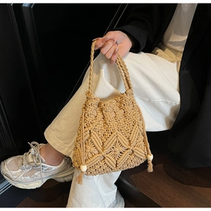 Détail de la texture macramé faite main avec perles en bois et pompons sur un sac beige