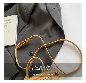 Detail of light brown leather bucket bag with adjustable strap and gold metal hardware