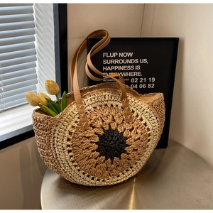Close-up detail of a handmade straw tote bag with a sunflower pattern and leather handles