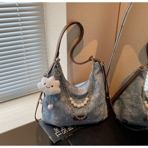 Detail of light blue denim tote with white floral motifs and silver chains with pearls