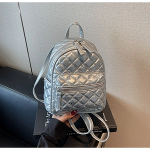 Detail of silver quilted mini backpack with sparkling rhinestone accents and zip pocket