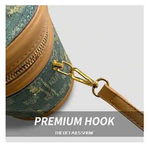 Close-up of golden metal hook and brown leather trim on a blue denim bucket bag