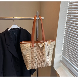 Détail du sac cabas en paille tressée avec bordure en cuir marron et nœud en dentelle