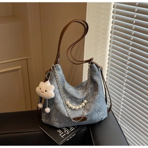 Detail of light blue denim texture bag with pearl chain and white cloud plush charm