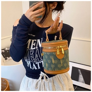 Close-up of monogram denim bucket bag with brown leather handles and gold zippers