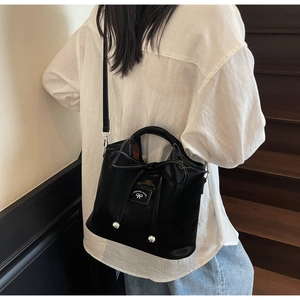 Detail of black bucket bag with ribbon bow and silver metal beads in a lifestyle setting