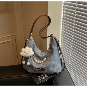 Detail of blue patterned canvas hobo bag with pearl chain and cloud plush charm