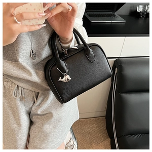Close-up of black lychee leather Boston bag with silver dolphin charm and hardware detail