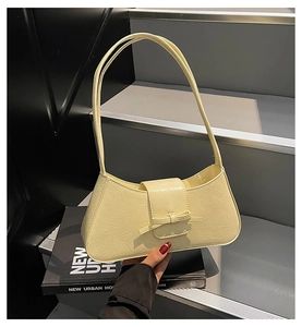 Detail of a creamy yellow underarm bag with a stylish bow and pleated faux leather texture