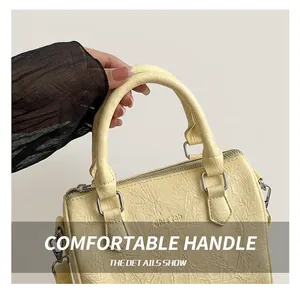 Detailed close-up of textured pale yellow handbag featuring silver D-rings and sturdy handle