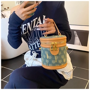 Detail of a denim monogram bucket bag with brown leather trim and golden hardware