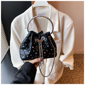Detailed view of black quilted bucket bag with rhinestones, metal handle, and pearl charm