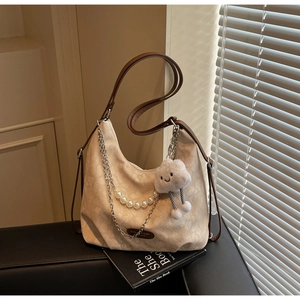 Detail of beige large tote bag with pearl chain, metal link, and plush cloud charm