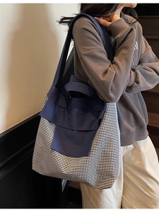 Large blue canvas tote bag with checkered details and long shoulder strap for commuting