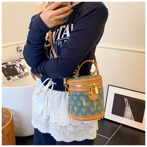Detail of denim blue monogram bucket bag showing texture, leather trim and gold hardware