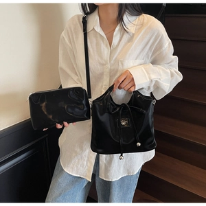 Detail of elegant black bucket bag and pouch set with bow accent shown on a model