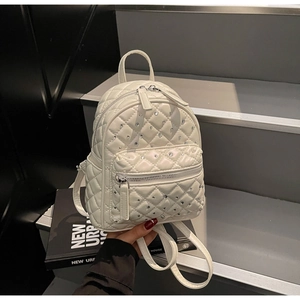 Detailed macro view of white quilted mini backpack with rhinestone studs and top handle