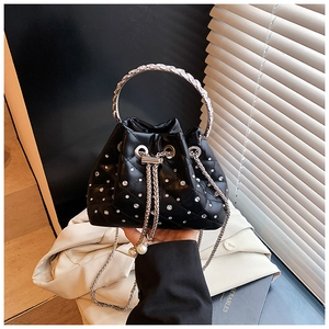 Detailed close-up of a black quilted rhinestone bucket bag with a pearl drawstring and chain