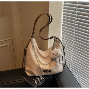 Detail of cream canvas tote bag with brown leather straps and pearl metal chain decoration