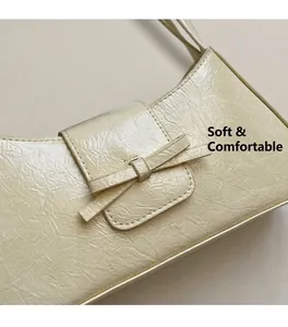 Close-up of cream shoulder bag featuring pleated texture and matching bow detail