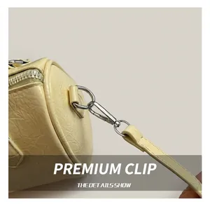 Close-up of silver metal hook and textured yellow leather on a cylinder bag
