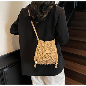 Détail d'un sac en paille tressé à la main avec glands en perles de bois et bandoulière