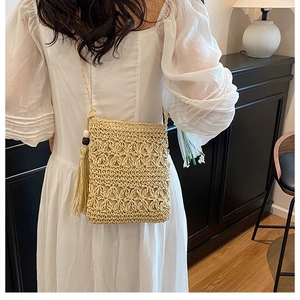 Detail view of handmade beige woven crossbody bag with 3D floral crochet and side tassels
