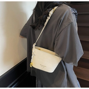 Detailed view of white crocodile pattern bucket bag with gold zipper and adjustable strap