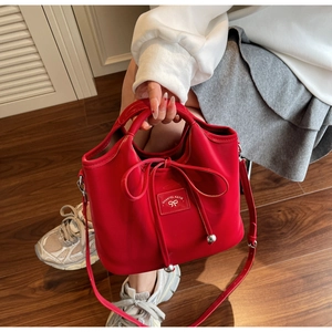Detail of red bucket bag with bow drawstring and SHANTEL KATIE logo on front