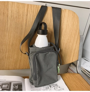 Detail of dark grey nylon water bottle crossbody bag with drawstring closure and zip pocket