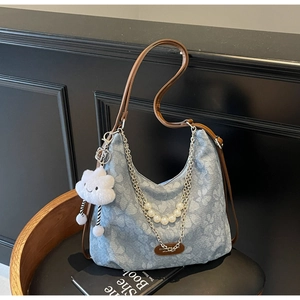 Detail of light blue floral denim tote bag with pearl chain and cloud plush pendant