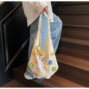 Close-up of white crochet tote bag with colorful 3D floral accents and rainbow strap