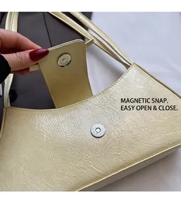 Detailed view of the magnetic buckle closure on a cream-colored textured leather handbag