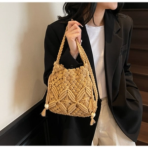 Détail du sac seau en paille beige avec tissage géométrique et glands perlés