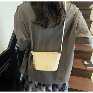 Detail of white crocodile pattern bucket bag with knot tassel and golden heart charm