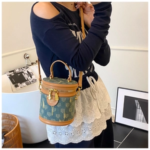 Detail of teal floral fabric and brown leather trim on the bucket bag shown by model