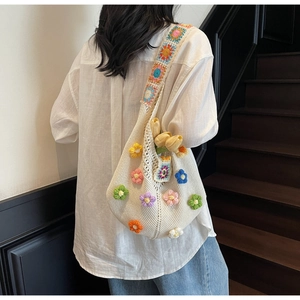 Close-up of bohemian knit tote bag with 3D floral accents and crochet shoulder strap