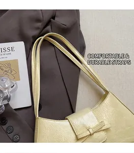Detail of cream yellow underarm bag with pleated texture and soft bow decoration