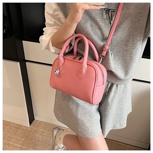Detail of pink lychee grain crossbody bag with silver charm and detachable shoulder strap