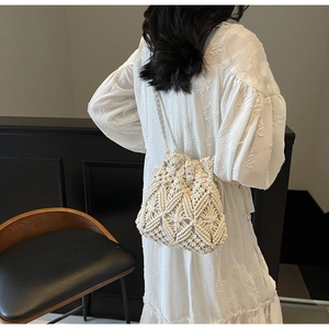Détail du tissage macramé complexe sur un sac seau bandoulière de couleur crème pour l'été