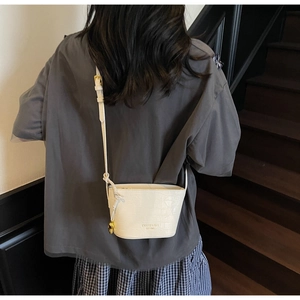 White faux leather bucket bag with crocodile pattern and thin strap shown on model