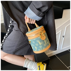 Detailed shot of a denim bucket bag with leather handles and jacquard pattern