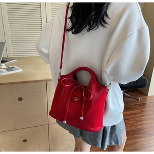 Detail of red leather bucket bag with bow tie closure and silver bead accents