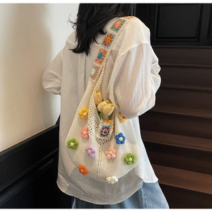 Detail of handmade crochet tote bag with colorful 3D flower motifs and wide knit strap
