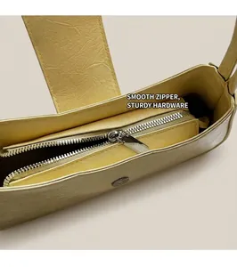 Detail of a smooth metal zipper on a cream pleated shoulder bag with wrinkled texture